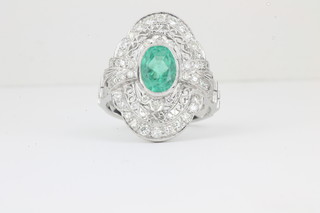 A lady's Art Deco style 18ct white gold dress ring set an oval emerald surrounded by diamonds