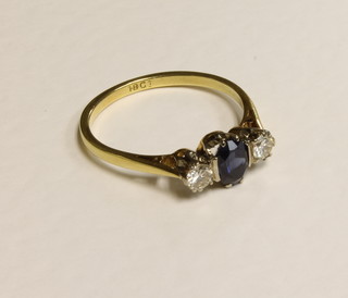 An 18ct gold dress ring set an oval sapphire supported by 2  diamonds