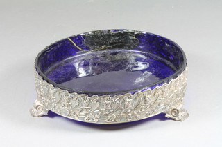 An Art Nouveau circular silver embossed dish decorated flower  heads, raised on 3 panel supports, Chester 1906, makers mark  Thomas Latham & Ernest Morton, blue glass liner - f, 6 ozs