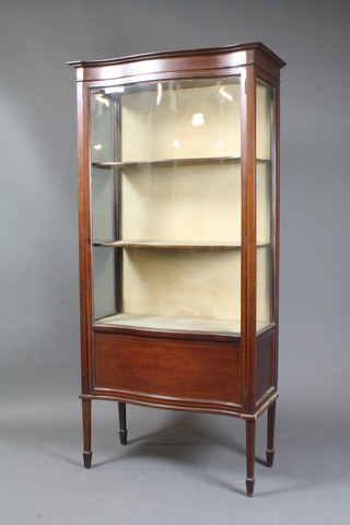 An Edwardian inlaid mahogany serpentine fronted display cabinet, fitted shelves enclosed by a glazed panelled door, raised  on square tapering supports, spade feet 68"h x 33"w x 16"d