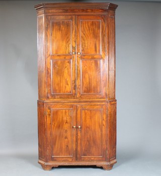 A George II oak double corner cabinet, the top with moulded  cornice, the upper section fitted shelves, the base enclosed by a  panelled door with stop-fluted pilasters to the sides, 82"h x 42"w  x 23"d