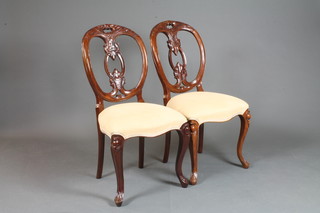 A set of 4 Victorian style mahogany hoop back dining chairs with carved splat backs and upholstered seats of serpentine outline, on  cabriole supports