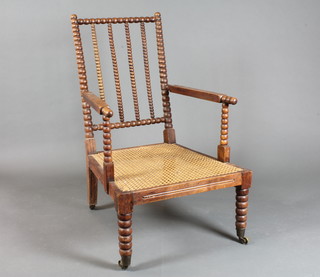 A Victorian turned rosewood open arm chair with bobbin turned decoration, caned seat