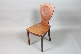 A late George III mahogany hall chair with shield back, solid seat, raised on square tapered legs, bears plaque to underside for   Druce & Company London