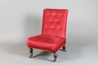 A Victorian nursing chair upholstered in red material raised on turned supports