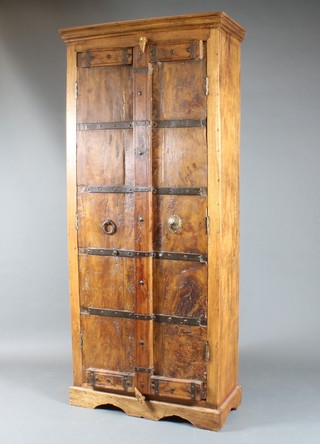 An Indonesian hardwood cabinet with moulded cornice, the  shelved interior enclosed by panelled doors 72"h x 32"w x 15"d