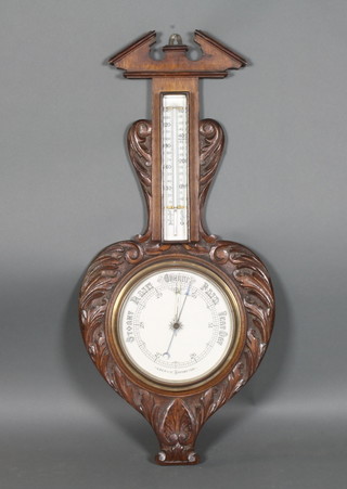 An Edwardian aneroid barometer and thermometer contained in a  carved oak wheel case