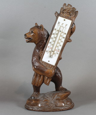 An early 20th Century Black Forest carved beechwood novelty thermometer, fashioned as a grizzly bear holding a section of  tree, having painted ceramic scale on naturalistic oval base 14"h,  bears label to verso for Pierre Michel Interlaken   ILLUSTRATED