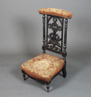 A mid Victorian Gothic revival ebonised Prie-Dieu chair, the splat  pierced with a crucifix and pierced foliate scrolls flanked by  turned columns, raised on turned tapered feet