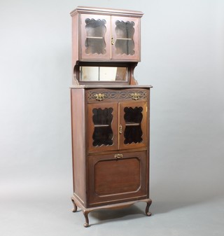 An Edwardian mahogany music cabinet, the raised upper section fitted a shelf enclosed by a panelled door above a recess with  plate mirrored back, the base fitted 1 long drawer with blind fret  work decoration above a cupboard enclosed by panelled doors  and fitted a music drawer, on cabriole supports 64"h x 22"w x  14"d