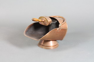 A copper helmet shaped coal scuttle with shovel