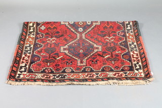 A red ground Persian rug with 3 stylised octagons to the centre  62" x 44"