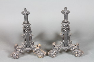 A pair of Victorian cast iron fire dogs, decorated grotesques