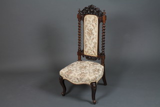 A mid Victorian rosewood low seat nursing chair in the 17th  Century style having a foliate scroll carved cresting rail above a  part padded back, flanked by barley twist supports, raised on  cabriole legs