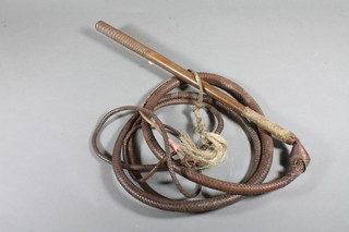 A leather bull whip with turned wooden handle