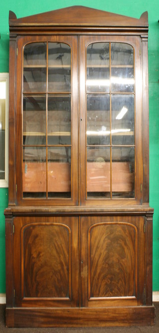 A Victorian mahogany bookcase cabinet with moulded cornice,  above adjustable shelves enclosed by astragal glazed doors, the  base with arch panelled doors, raised on a platform base 41.5"w  x 18"d x 94"h