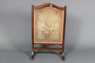 A Georgian style mahogany adjustable fire screen inset foliate woolwork panel and raised on splayed feet 36"h x 21"w x 13"d