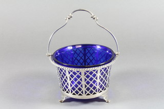 A circular silver basket with swing handle, raised on panel supports with blue glass liner, Birmingham 1937, 3 ozs,