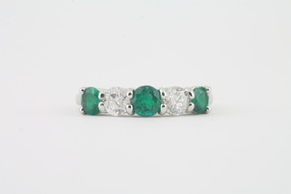An 18ct white gold dress ring set 3 emeralds approx. 0.81ct and  2 diamonds approx. 0.66ct