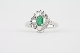 An 18ct white gold cluster dress ring set an emerald surrounded by diamonds