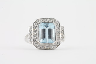 An 18ct white gold dress ring set a rectangular cut aquamarine surrounded by diamonds, approx 3/0.50ct