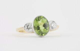 An 18ct yellow gold dress ring set an oval cut peridot supported by 2 diamonds