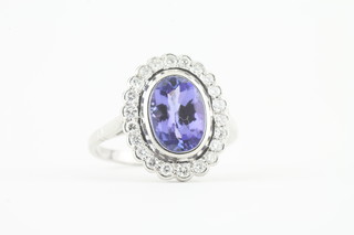 An 18ct white gold dress ring set an oval tanzanite surrounded by diamonds