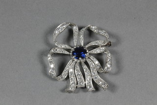 A white gold brooch of floral form set diamonds and a garnet to  the centre