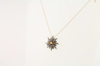 An 18ct white gold pendant in the form of a sun set diamonds,  hung on a gold chain