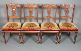 A set of 4 late Victorian walnut dining chairs in the Sheraton style, having broken arch cresting rails above pierced vase splats  and stuff over seats, raised on turned legs with peg feet