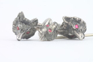 A silver stick pin in the form of a foxes mask the eyes set red stones, together with a pair of matching cufflinks
