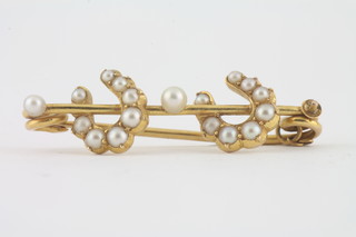 A yellow metal brooch in the form of two horse shoes set seed  pearls