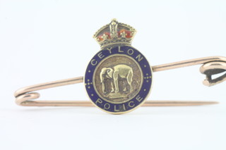 A 9ct gold chain and a yellow metal and enamelled Ceylon Police sweetheart brooch