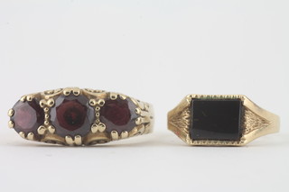 A 9ct gold dress ring set oval cut red stones together with a 9ct yellow gold signet ring set a rectangular black polished stone
