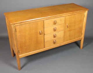 Gordon Russell Ltd of Broadway. A quarter sawn oak sideboard,  fitted 4 central short drawers, flanked by 2 cupboard doors  enclosing shelves, raised on chamfered tapered legs 34.5"h x  55"w x 19"d  ILLUSTRATED