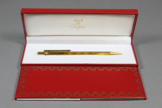 A Cartier ball point pen contained in a reeded gold plated case, marked B42914, cased and with original paperwork