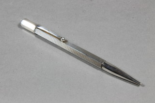 A silver propelling pencil contained in an engine turned case