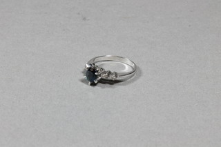 An 18ct white gold dress ring set an oval sapphire and with 4 diamonds to the shoulders
