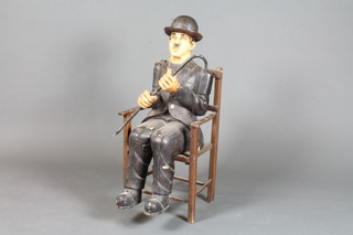 A carved wooden figure of Charlie Chaplin with cane, sat in a  beech ladder back carver chair 27"h x 15"w x 11"d