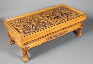 An unusual Eastern carved hardwood coffee table, the top profusely relief carved depicting a procession of elephants  through a rain forest, raised on foliate carved splayed legs 19"h x  50.5"w x 25"d