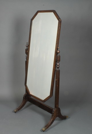 A 1920's oak cheval mirror, having octagonal plate raised on  splayed legs with brass caps and casters 61"h x 27"w x 20"d