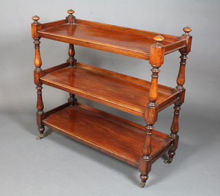 A Victorian mahogany 3 tier buffet having baluster column supports raised on turned feet with brass caps and casters 39"h x  40"w x 17"d