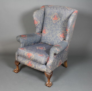 A George II style wing armchair having a foliate and geometric woven upholstery on acanthus leaf carved cabriole legs, claw and  ball feet
