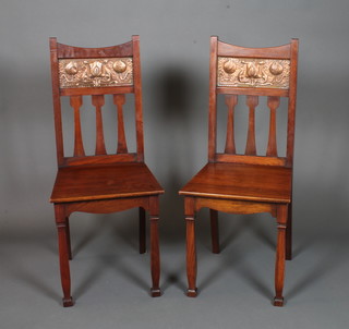 A pair of unusual English walnut Art Nouveau hall chairs, the shaped backs inset embossed copper panels of stylised flowers  above solid seats, raised on tapered shaped legs