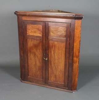 A George III mahogany hanging corner cupboard, having  moulded cornice above a pair of fielded panelled cupboard doors enclosing 2 shaped shelves with plinth base below 43"h x 39"w x  21"d