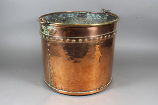 A copper coal bucket with brass swing handle