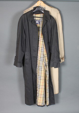A Burberry light coloured double breasted rain coat together with lady's Burberry black rain coat