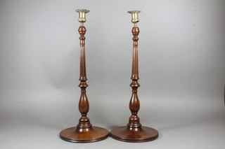 A pair of 19th Century turned and fluted mahogany candlesticks raised on circular bases with brass sconces 20"