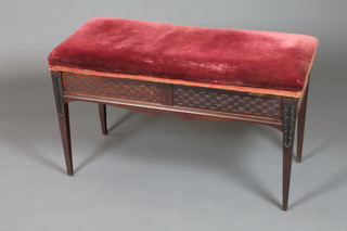 James Shoolbred & Co. Tottenham Court Road London, a late Victorian mahogany duet piano stool, having crimson velvet  hinged top, the frieze decorated floral lattice, raised on acanthus  leaf carved tapered legs, 21"h x 34"w x 15.5"d