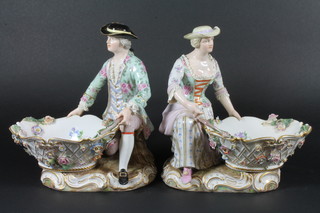 A pair of 19th Century Meissen porcelain sweetmeat dishes supported by a figure of gallant and belle, the base with cross  swords mark and incised H166 and impressed 74 8.5", fingers  missing and some chips  ILLUSTRATED
